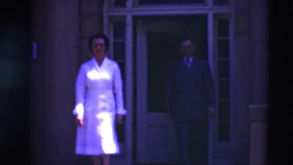 A woman in a white nurse-style uniform and a suited man appear near the entrance of a Paducah building in 1951 home-movie footage.