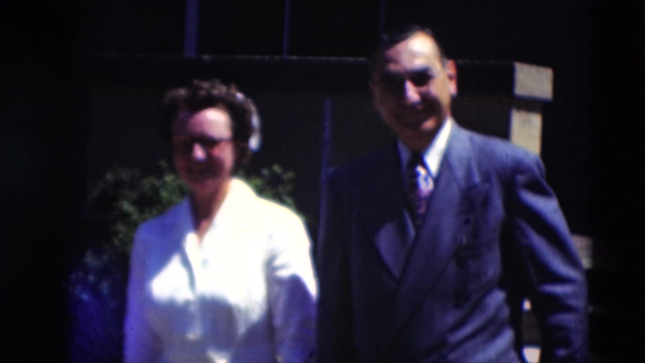 A woman in a white uniform and cap stands beside a suited man outdoors in the Paducah 1951 home-movie scene.