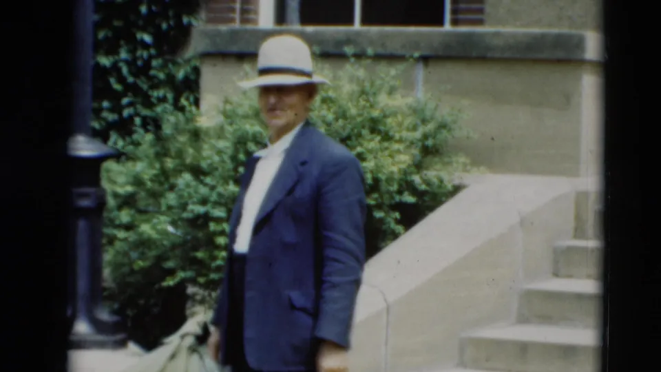 Adult man in a light fedora and dark suit stands outside on stone steps in 1951 Paducah, Kentucky home-movie footage.