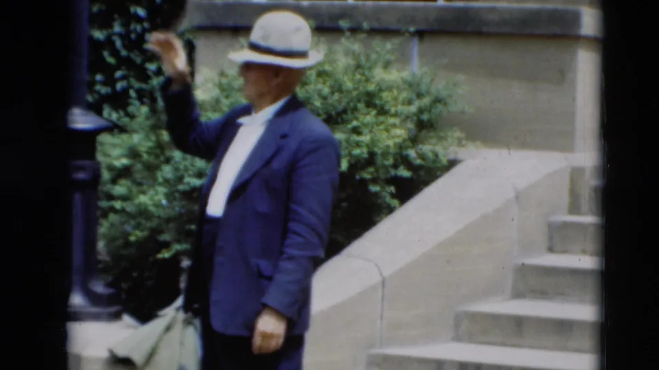 The fedora-wearing man continues the wave beside stone steps and shrubbery in the 1951 Paducah home movie.