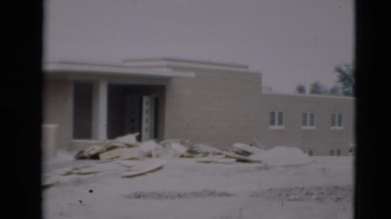 Closer view of the building entrance with columns, debris, sand, and small windows.