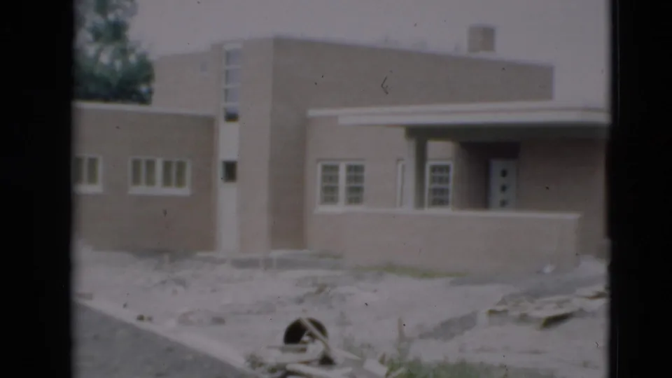 1951 Paducah frame of the building facade from a similar angle, showing white-framed windows, a recessed entrance, and unfinished grounds.