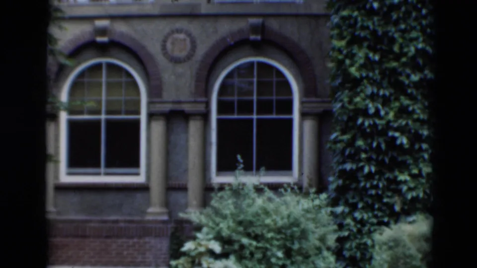 1951 Paducah frame showing an ornate building facade with arched windows, columns, brickwork, shrubs, and ivy-covered wall.