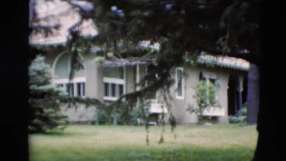 1951 Paducah home-movie view of a pale residence with an arched window, shrubs, and a broad lawn.