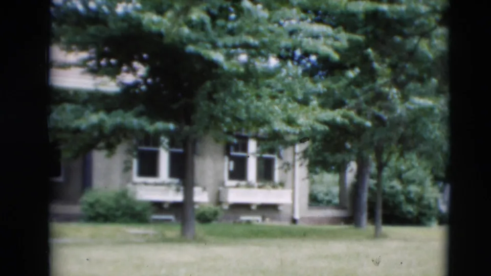 1951 Paducah frame showing a house facade with windows, a shaded lawn, shrubs, and leafy trees in the foreground.