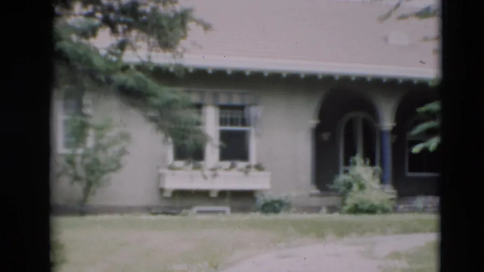 1951 Paducah home-movie frame with a closer view of the house facade, window box, arched doorway, shrubs, lawn, and path.
