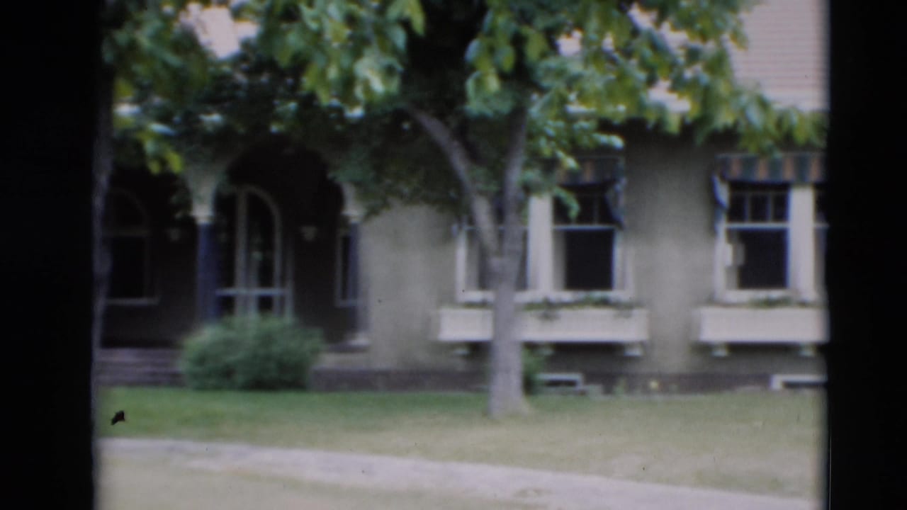 1951 Paducah residential view showing a large house with arched doorways, window boxes, trees, lawn, and sidewalk in soft 8mm focus.