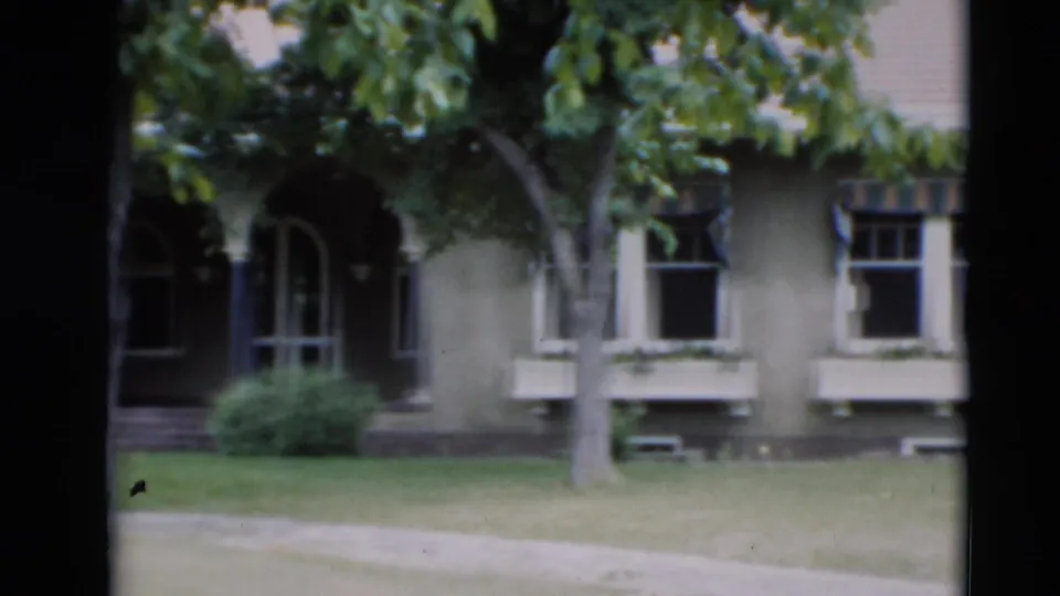 1951 Paducah residential view showing a large house with arched doorways, window boxes, trees, lawn, and sidewalk in soft 8mm focus.