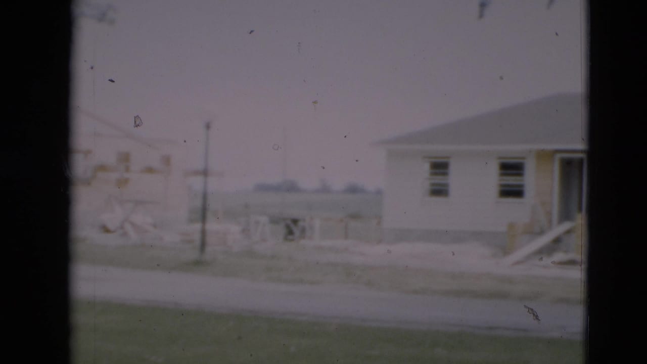 1951 Paducah frame showing a new residential lot with a house edge, open framing, utility pole, and road in soft focus.