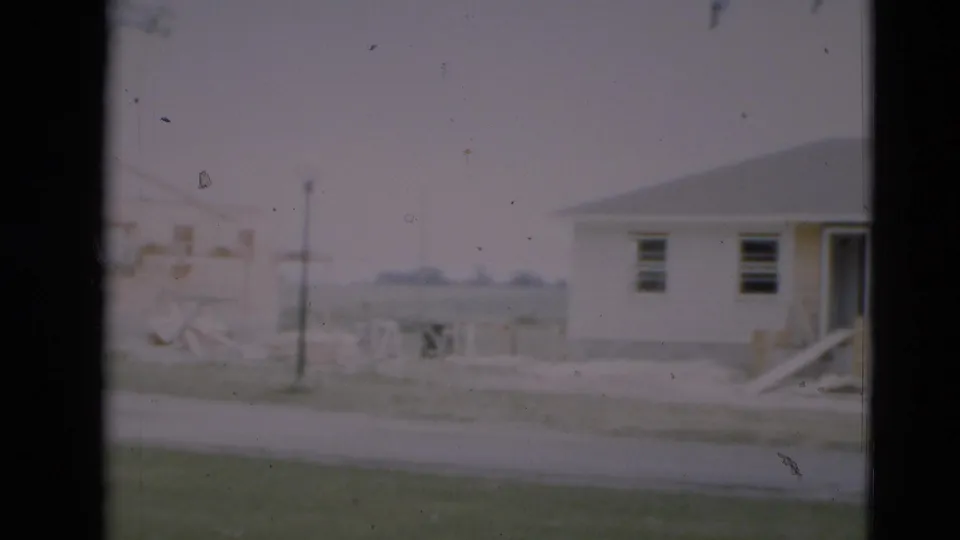 1951 Paducah frame showing a new residential lot with a house edge, open framing, utility pole, and road in soft focus.