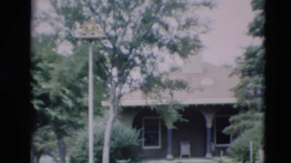 1951 Paducah residential exterior with a birdhouse pole, mature trees, and a shaded porch partly obscured by foliage.
