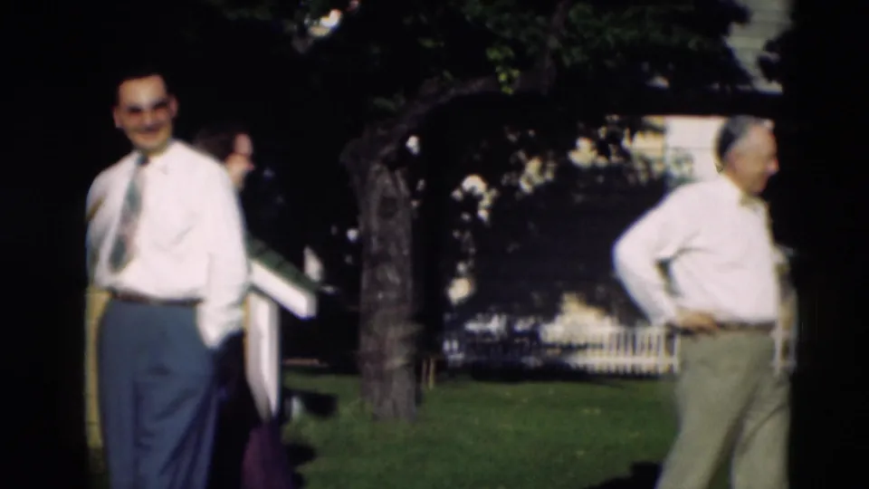 Men in white shirts and ties stand apart on a shaded Paducah lawn, with trees and a white fence behind them.
