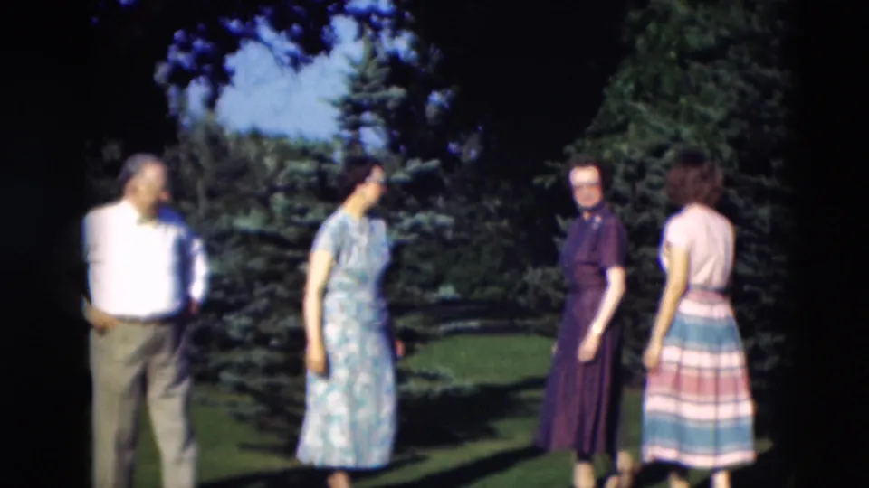 A man in a white shirt and three women stand together on a Paducah backyard lawn in 1951 home-movie footage.