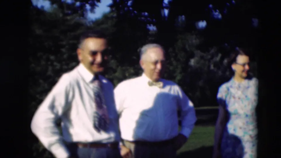 Close 1951 home-movie view of two men in shirts and a woman in a patterned dress standing on a Paducah lawn.