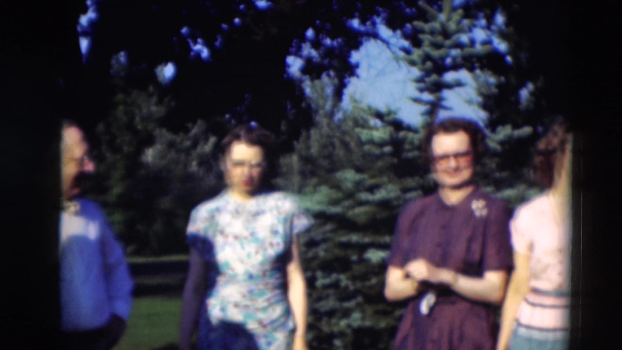 Adults in 1951 Paducah footage stand near evergreen trees, with a man in a dark shirt and women in patterned and pale tops.