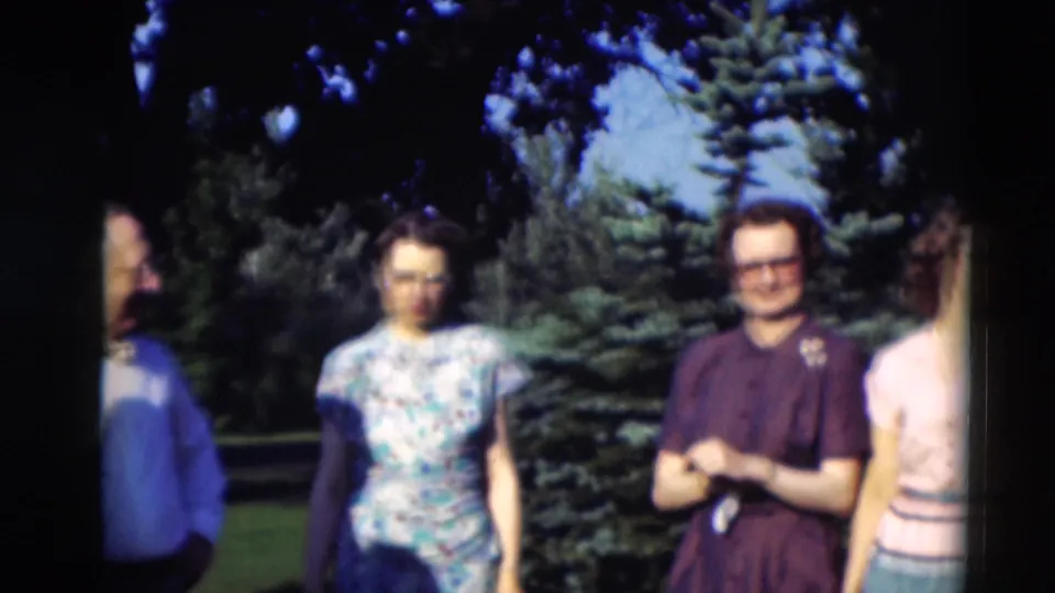 Adults in 1951 Paducah footage stand near evergreen trees, with a man in a dark shirt and women in patterned and pale tops.