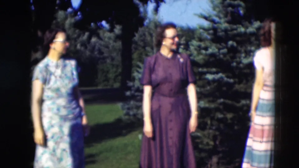 Three women in patterned 1950s dresses stand outdoors in a Paducah, Kentucky garden, with evergreens and lawn behind them.