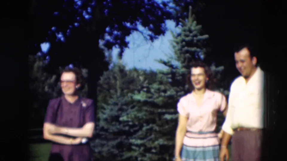 Two women and a man stand together in the Paducah garden, with the group smiling near evergreens and shaded grass.