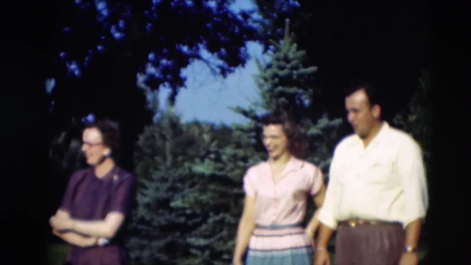 1951 Paducah home-movie frame showing three adults in a grassy yard, including a woman in purple and a couple in period clothing.