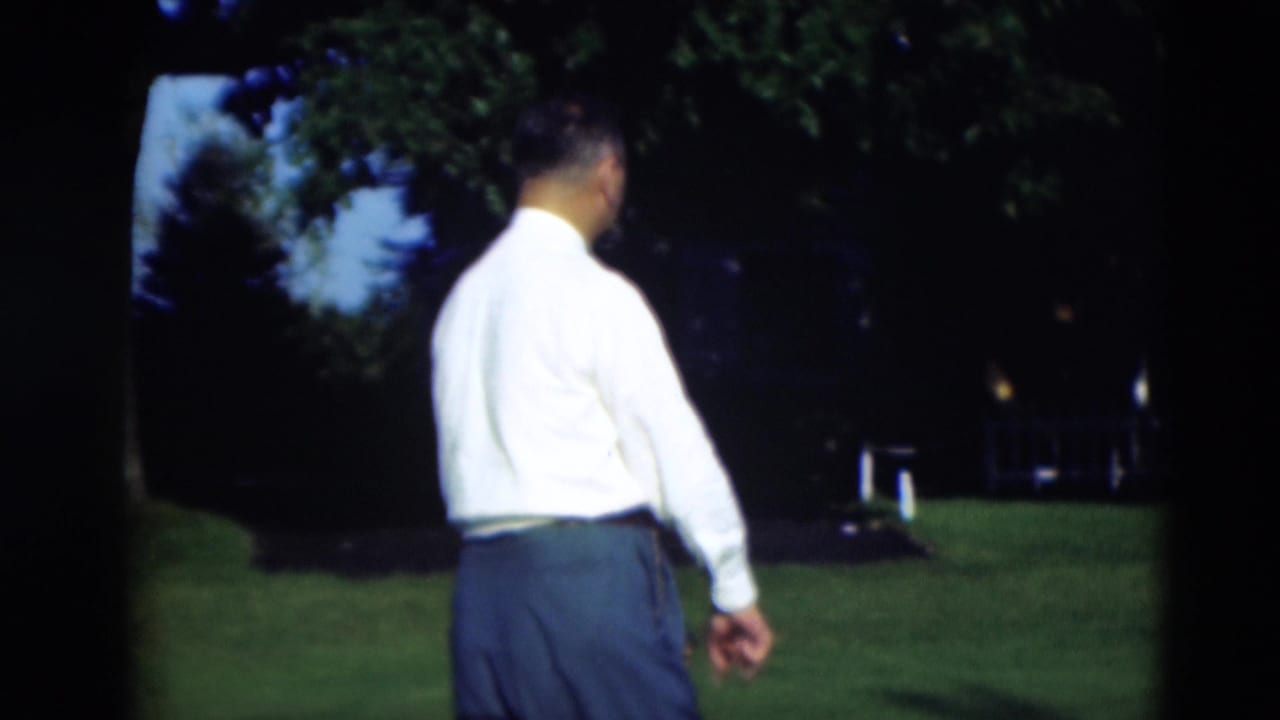 Adult man in a white shirt and dark trousers walks away across a Paducah, Kentucky lawn in 1951 home-movie footage.