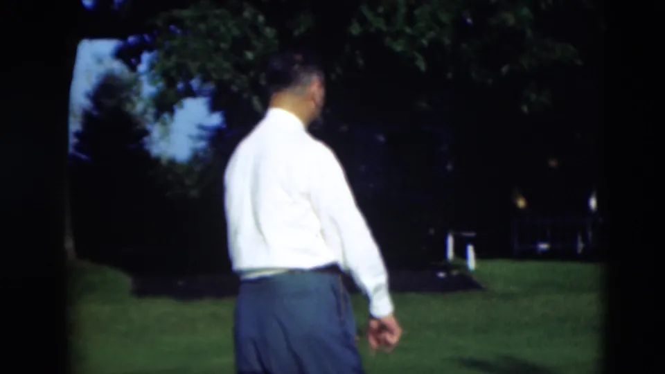 Adult man in a white shirt and dark trousers walks away across a Paducah, Kentucky lawn in 1951 home-movie footage.