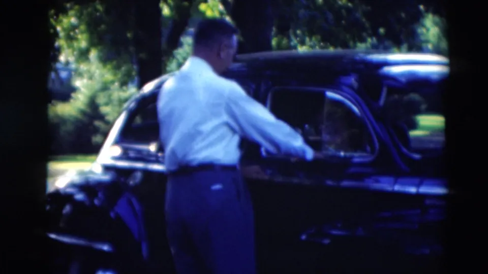 The man reaches toward the dark car's side or door area, apparently completing the assistance gesture in the 1951 Paducah home movie.