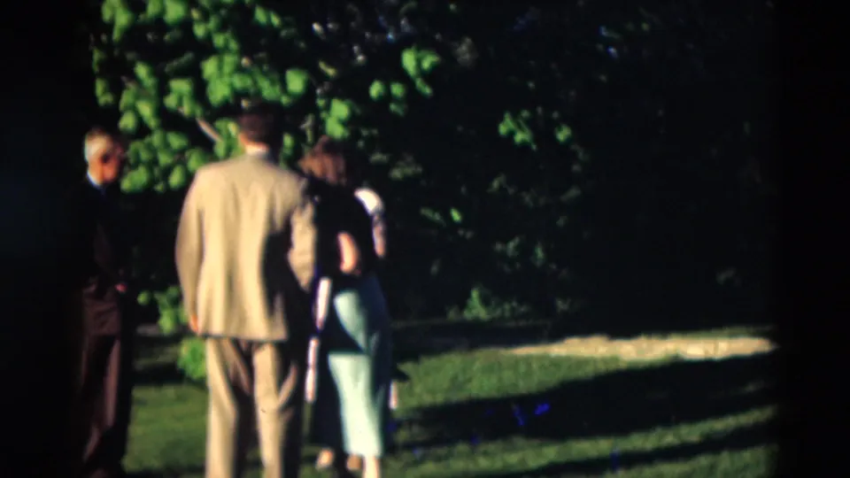 1951 Paducah outdoor gathering with adults in formal clothing standing on grass near a shaded tree line.