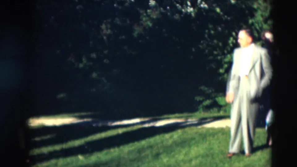 In supplied 1951 Paducah home-movie footage, a man in a light suit stands on grass with trees and a path behind him.