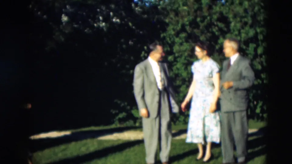 Three adults, two men in suits and a woman in a floral dress, appear to converse on a lawn in Paducah, Kentucky, per metadata.