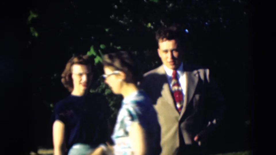 1951 Paducah home-movie frame showing three adults in a garden, including a man in a light suit and women in dark and floral tops.