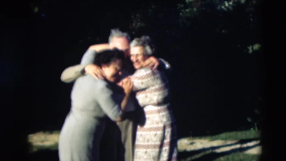 1951 Paducah frame of adults in a close family embrace, partly obscured by shade and soft 8mm focus.