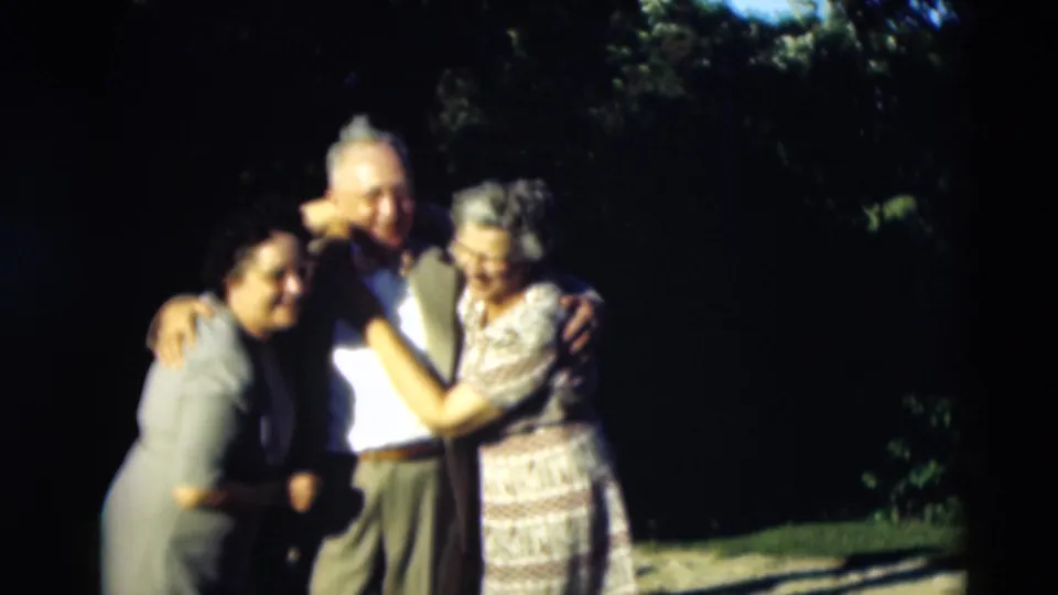 The final frame shows the three adults in Paducah still gathered in a close embrace, softened by 8mm blur and strong daylight contrast.