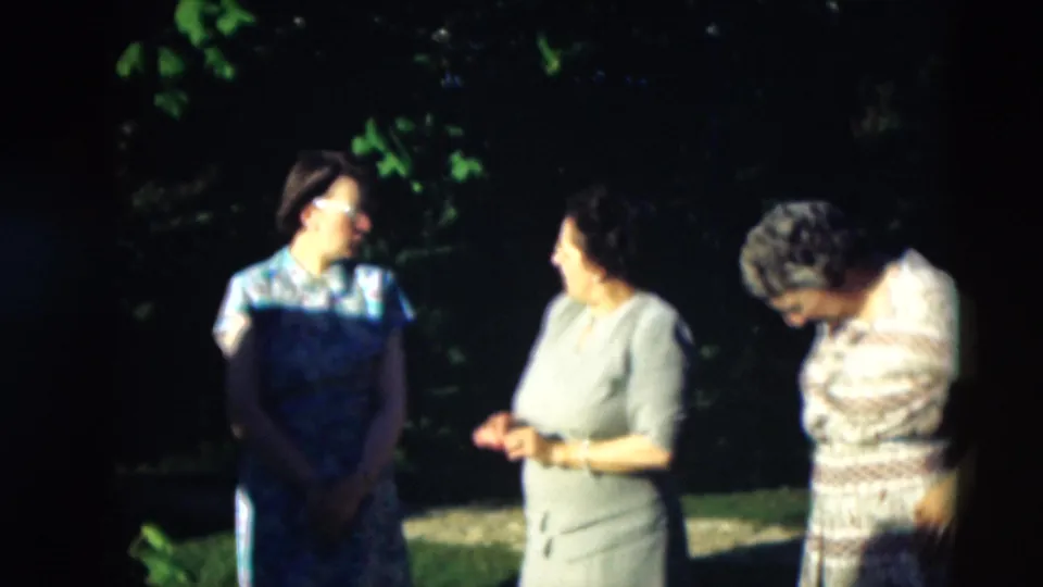 Three women remain in conversation outdoors in 1951 Paducah footage, with one woman in a patterned dress bending at the right.
