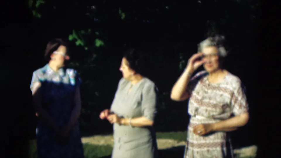 1951 Paducah outdoor frame with three women in mid-century dresses, one adjusting her glasses as the others face her.