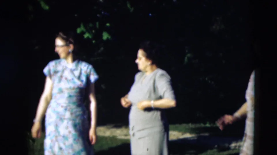 Two women in mid-century dresses stand in a leafy outdoor setting in 1951 Paducah, Kentucky footage.