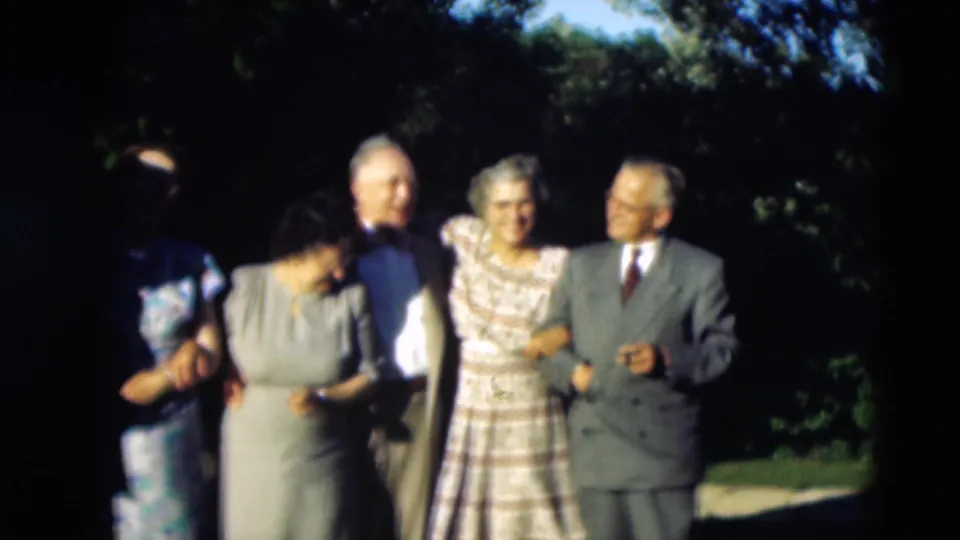A larger cluster of adults in suits and dresses poses outdoors in this 1951 home-movie frame from Paducah, Kentucky.