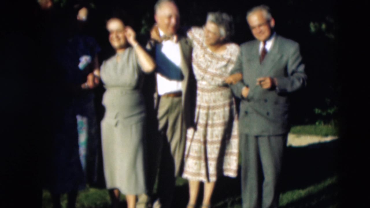 In 1951 Paducah, Kentucky home-movie footage, adults in dresses and suits pose together outdoors on a shaded lawn.