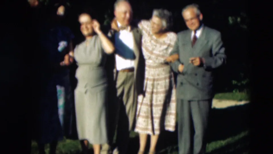 In 1951 Paducah, Kentucky home-movie footage, adults in dresses and suits pose together outdoors on a shaded lawn.