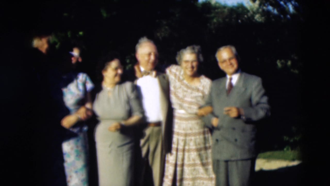Adults in mid-century formal clothing stand arm in arm outdoors in the supplied 1951 Paducah home-movie scene.
