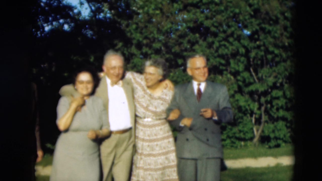 In 1951 Paducah home-movie footage, four well-dressed elderly adults stand together outdoors in daylight near trees and grass.