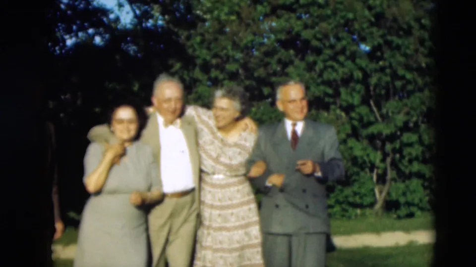 In 1951 Paducah home-movie footage, four well-dressed elderly adults stand together outdoors in daylight near trees and grass.