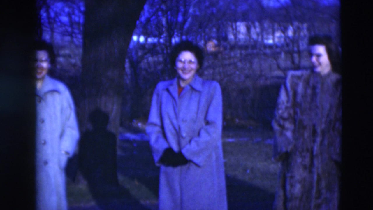 Three adults in winter coats stand near a tree in 1951 Paducah footage, with one figure partly obscured by the trunk.