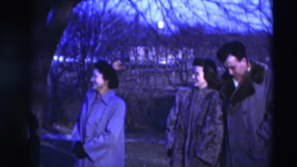 Several adults in winter coats gather near trees in 1951 Paducah home-movie footage, looking toward each other in conversation.
