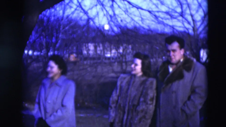 In 1951 Paducah, Kentucky footage, three adults in heavy coats stand outdoors beneath bare branches in blue dusk light.