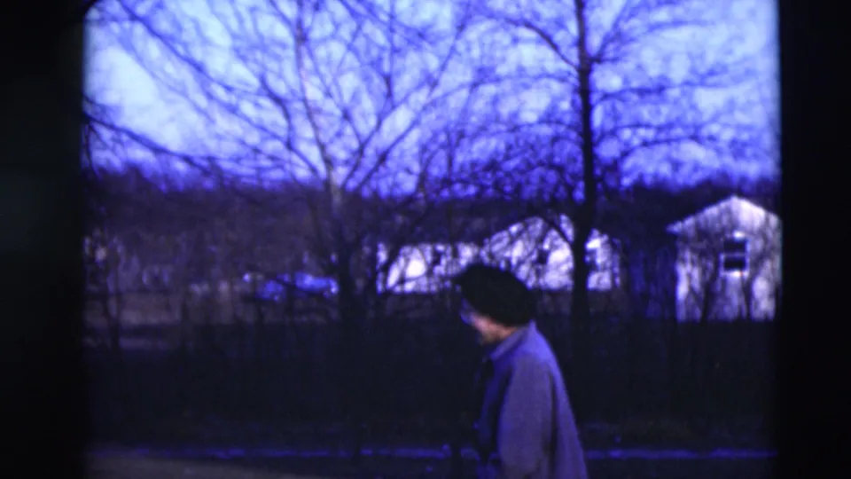 A woman in winter clothing looks toward modest houses and leafless trees in the Paducah neighborhood setting.