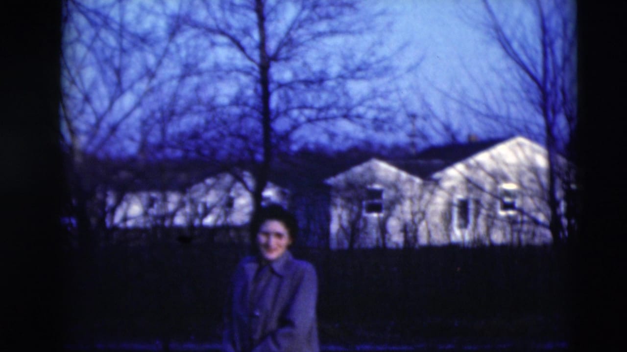 A woman smiles toward the camera in 1951 Paducah, with leafless trees and residential houses behind her.
