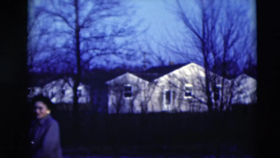 The woman moves near the edge of the frame as Paducah residential houses and winterlike trees remain visible behind her.