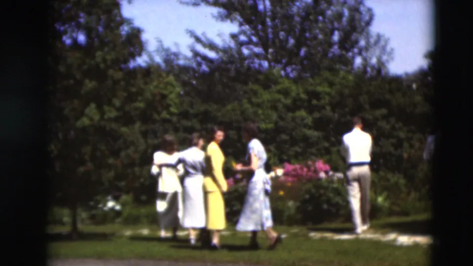 Adults in mid-century clothing gather near blooming flowers and shrubs in Paducah, Kentucky footage from 1951.