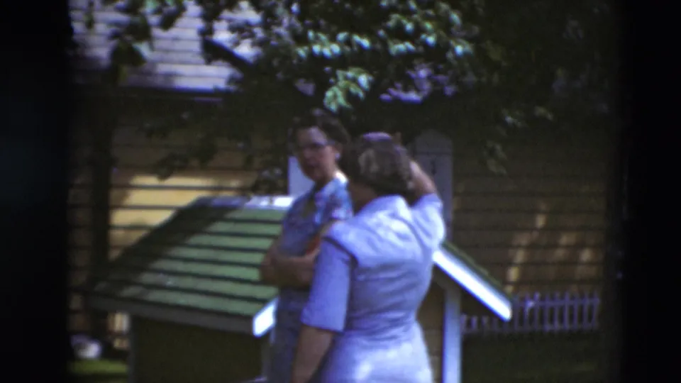 Two adults stand near a house, steps, and a small roofed yard structure in a sunny Paducah residential setting from 1951.
