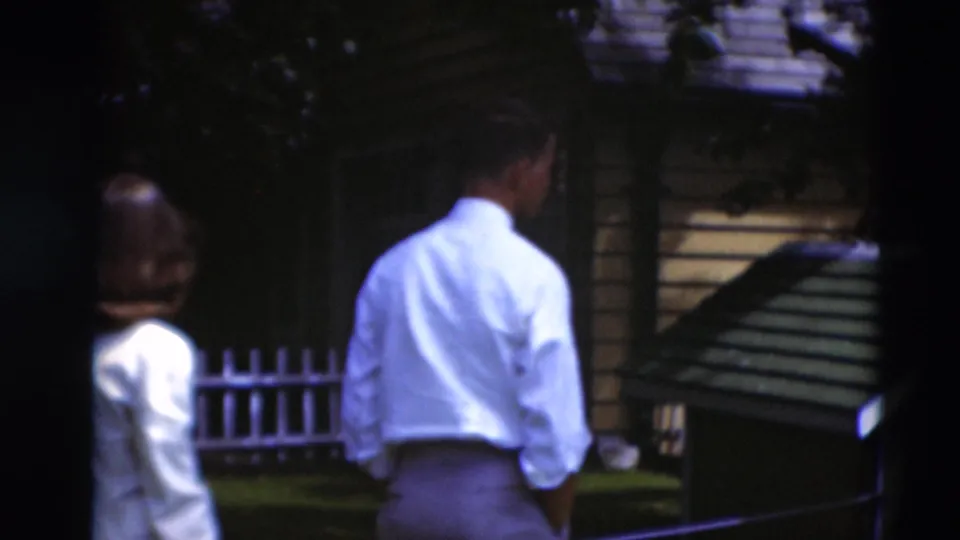 1951 Paducah backyard view with adults near a small wooden structure and a white picket fence.
